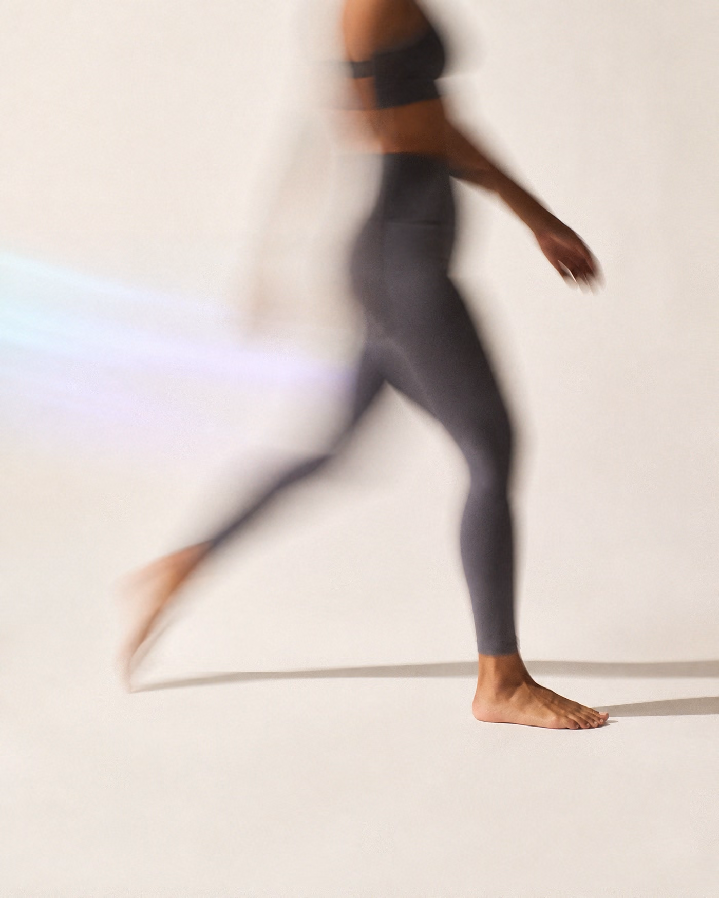 Una figura a media zancada sobre fondo crema, el cuerpo barrido por el movimiento y el pie apoyado nítido