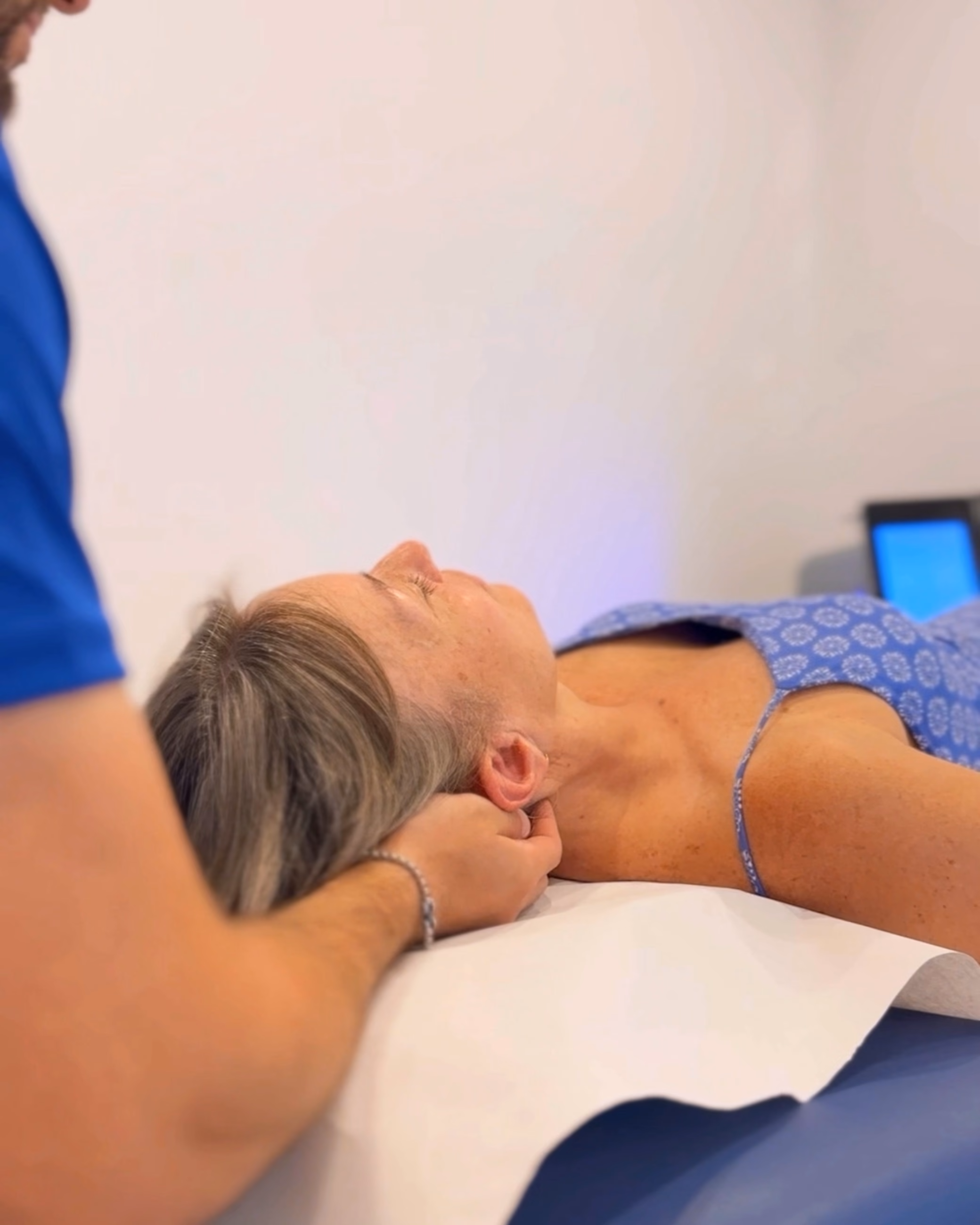 Terapia manual sobre el cuello de una paciente tumbada en la camilla