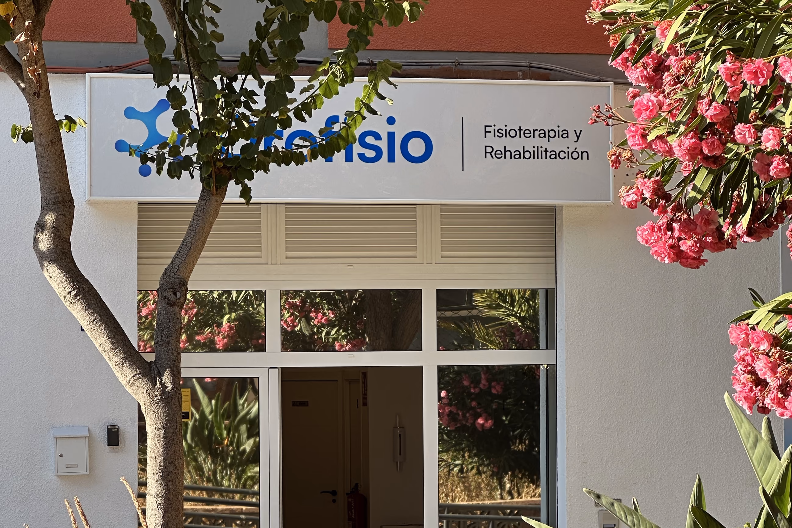 Fachada de la clínica Orofisio en La Cuesta, La Laguna, con una buganvilla en flor delante del rótulo